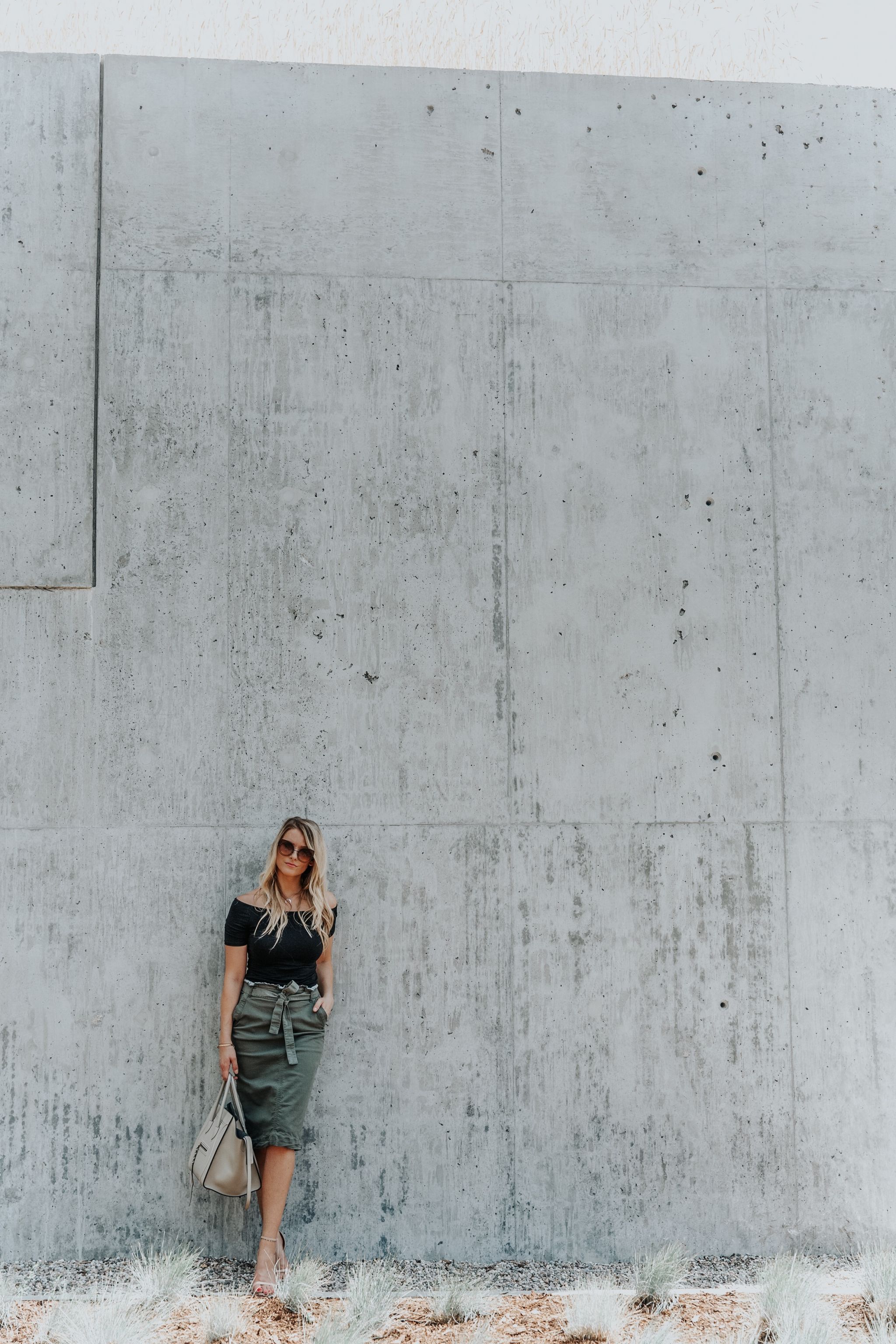 1 person, fashion blogger standing against large concrete wall