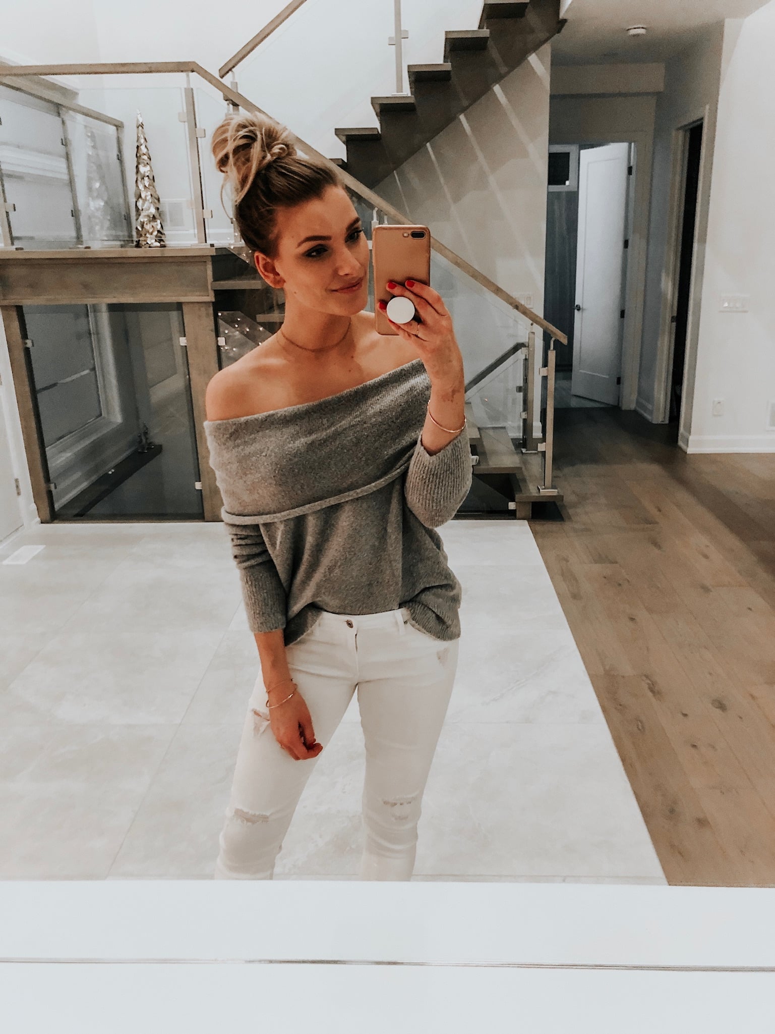 girl wearing off shoulder grey sweater and white jeans taking a selfie