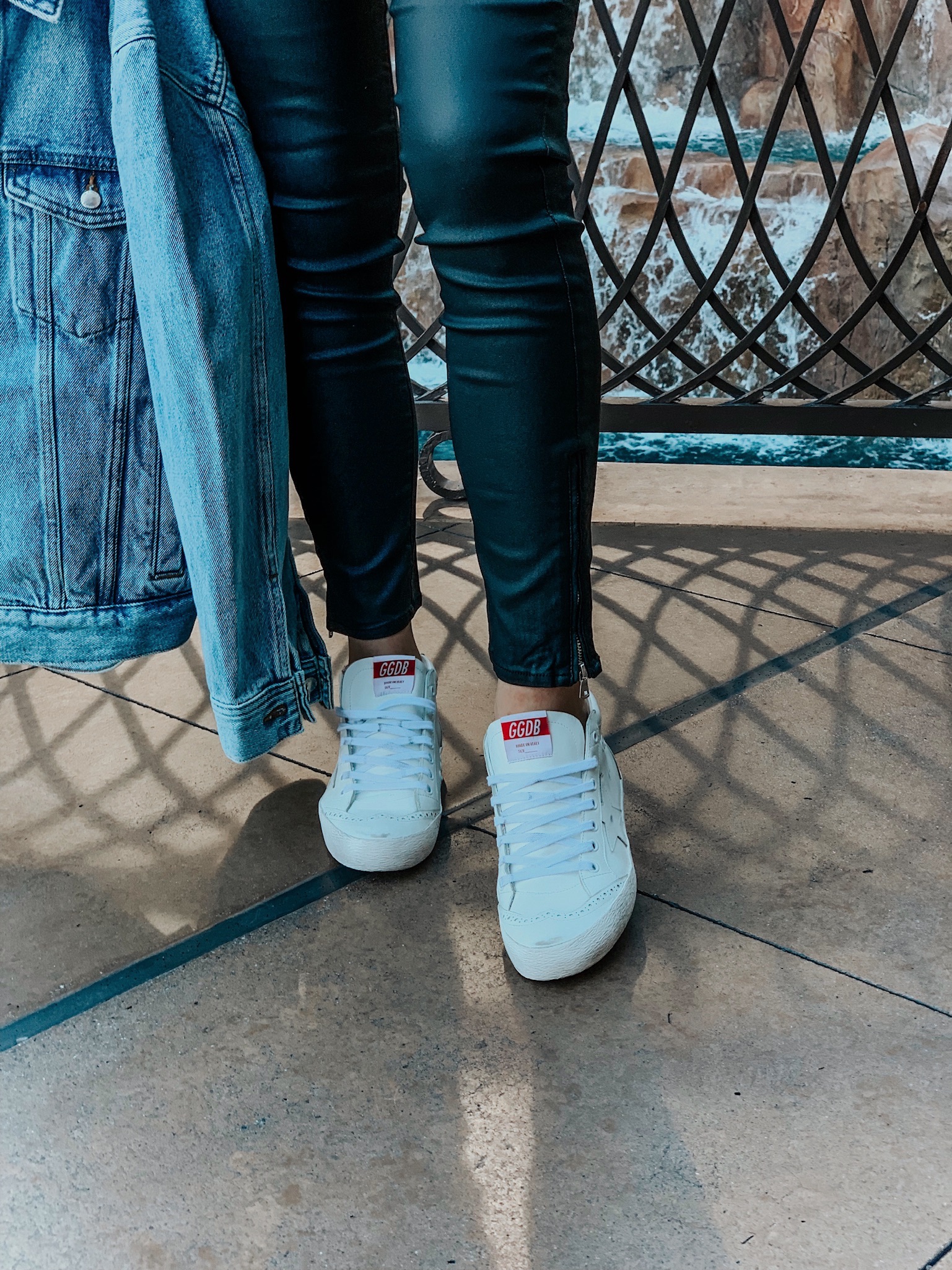 girl wearing white mid star golden goose sneakers and holding a denim jacket